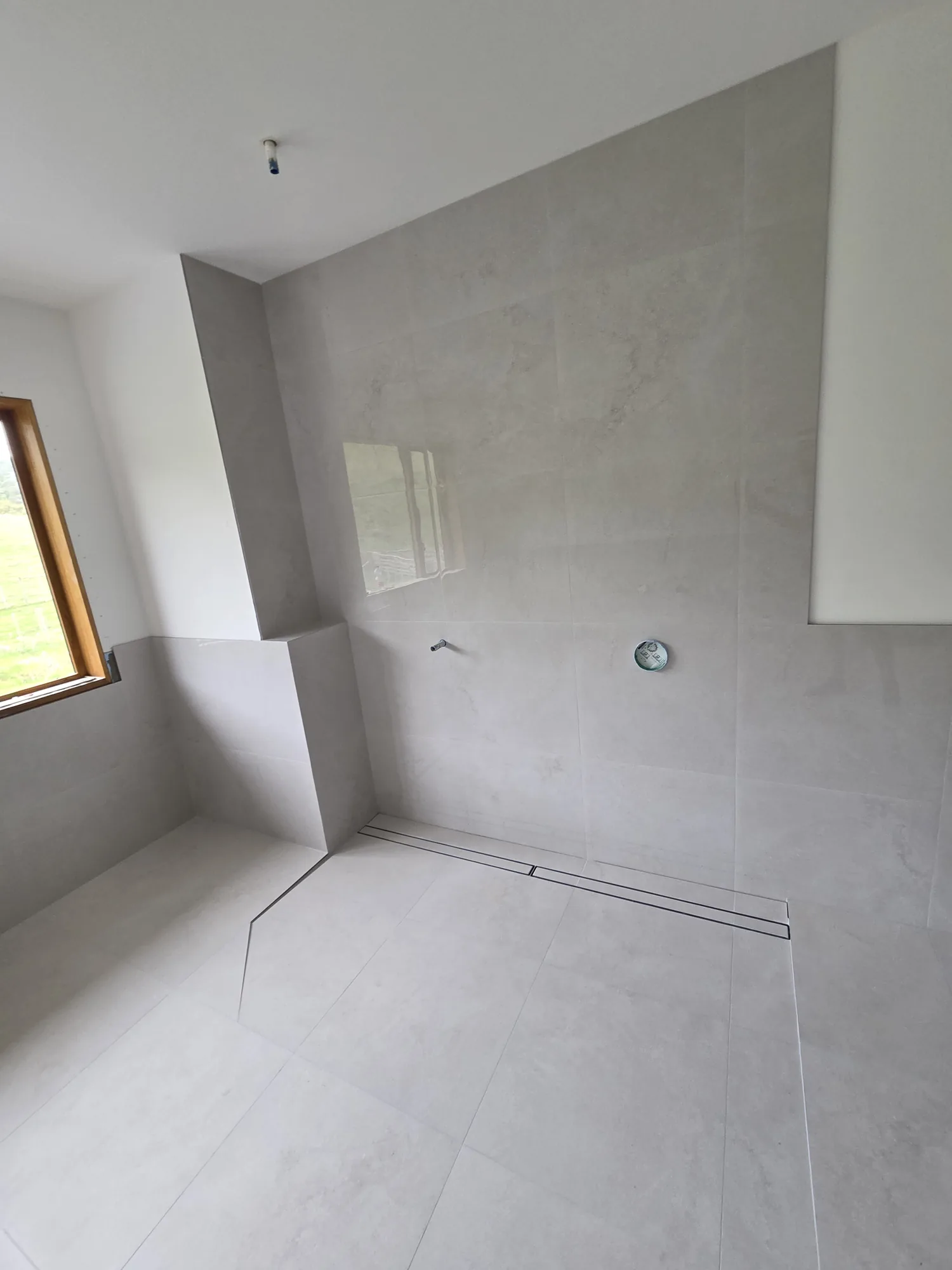 Custom fully tiled walk-in shower with linear drain and tiled bench in a Clevedon new-build bathroom — by Tarara Tiling