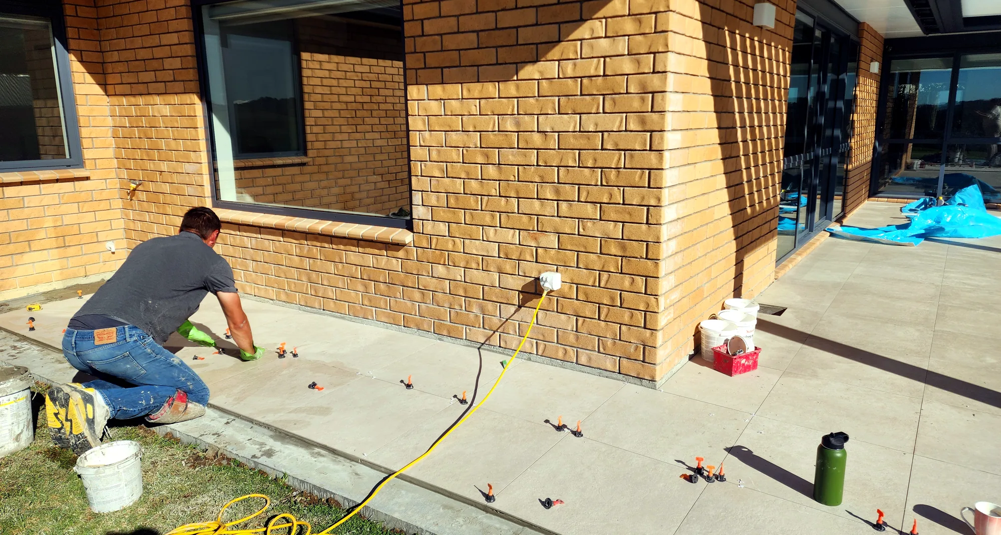 Marko laying outdoor floor tiles around a brick home in Auckland