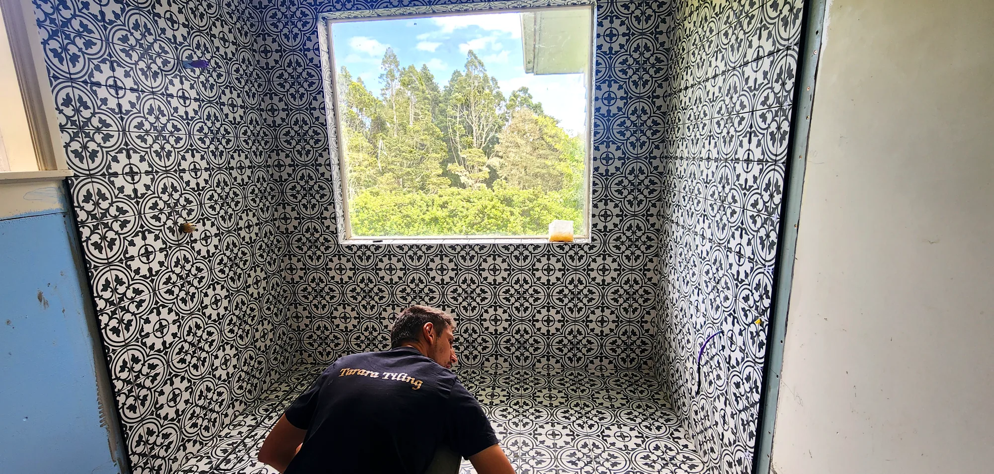 Marko tiling a blue-and-white patterned feature bathroom in Auckland