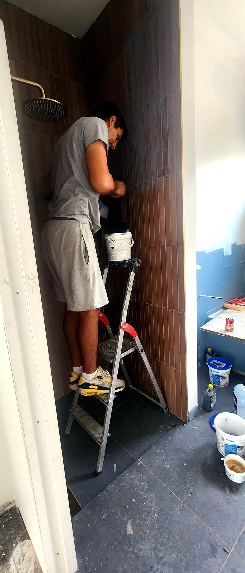Marko installing wood-look tiles on a shower wall in an Auckland bathroom