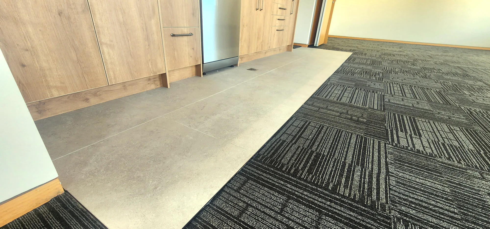 Clean diagonal transition between floor tiles and carpet tiles in an Auckland office fit-out — tiling by Tarara Tiling