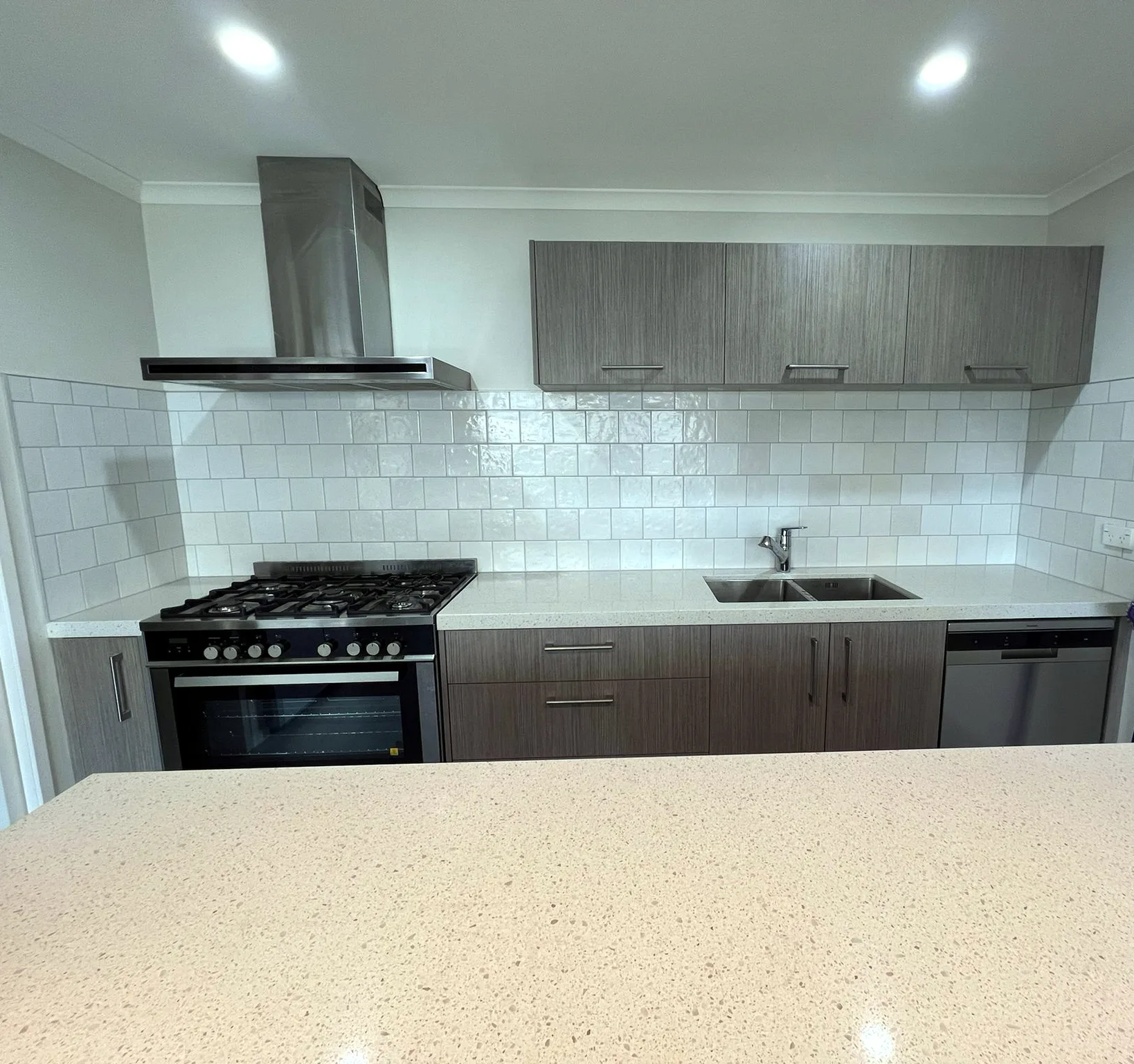 Gloss white square-tile kitchen splashback behind a freestanding cooker, Auckland — tiling by Tarara Tiling